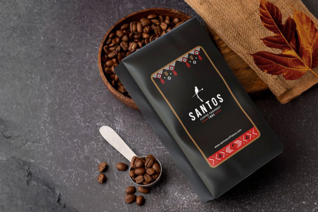 Bag of Santos Coffee with coffee beans and spoon on dark textured surface, representing fresh Guatemalan coffee for subscription delivery.