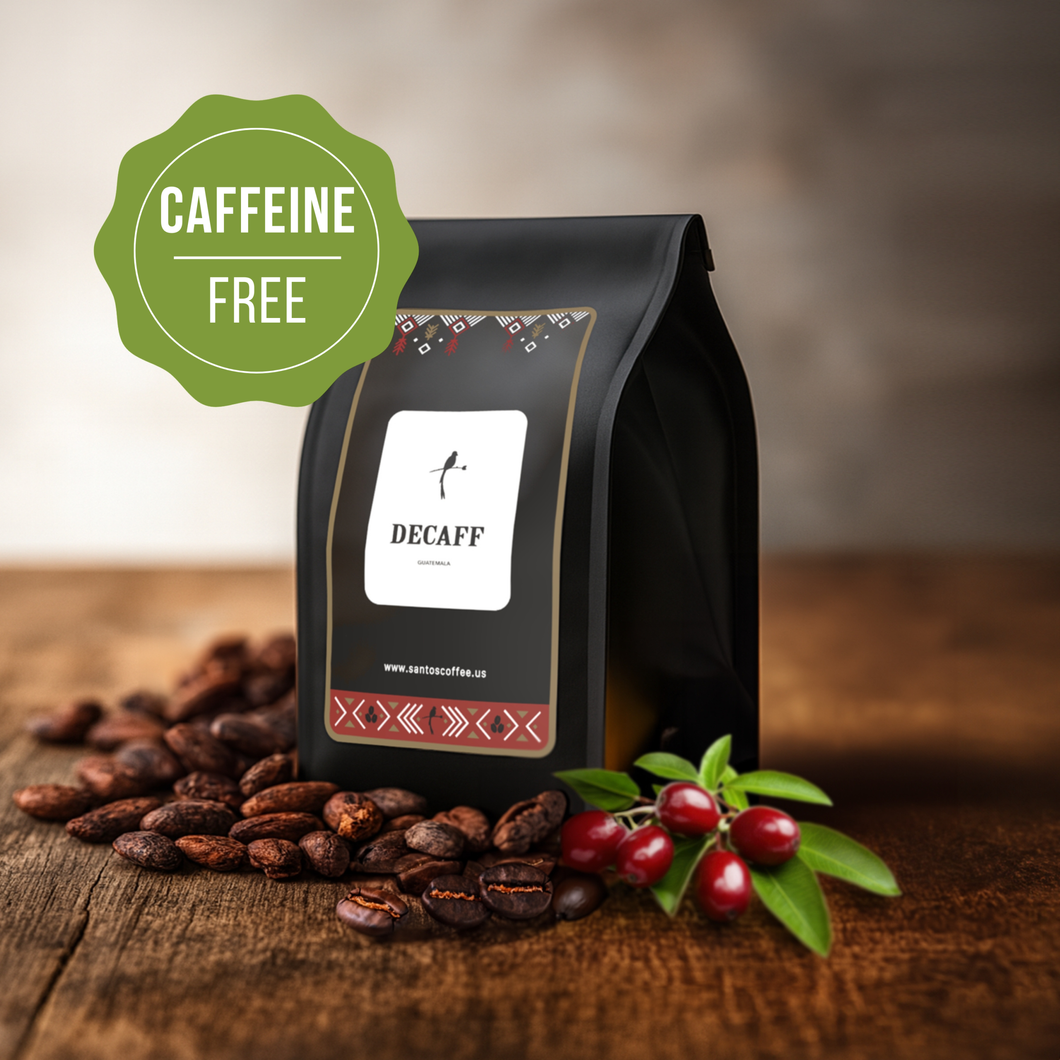 Santos Coffee Decaf Coffee bag labeled “Caffeine Free,” surrounded by roasted coffee beans and fresh coffee cherries on a wooden table.