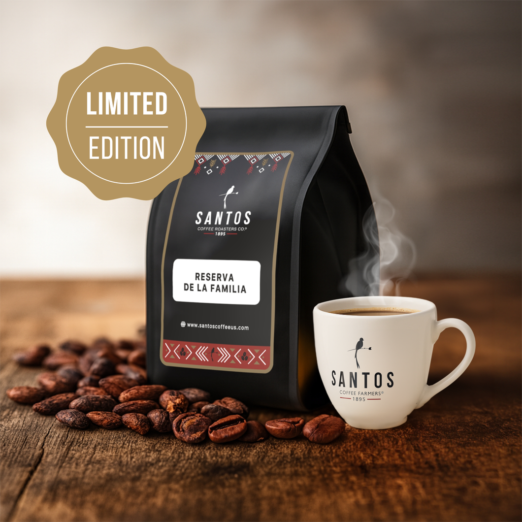 Santos Coffee Reserva de la Familia Limited Edition coffee bag beside a steaming cup of coffee and scattered beans on a rustic wooden table.